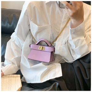 Dettaglio mini borsa lavanda con chiusura a scatto dorata e tracolla a catena sul modello