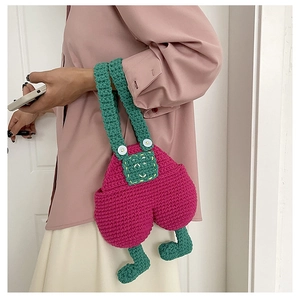 Detail of handmade crochet crossbody bag with unique overall pants design and green straps