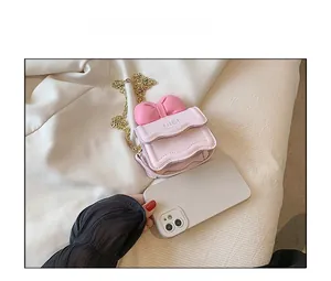 Comparaison de taille détaillée du mini sac bandoulière rose avec nœud et chaîne dorée