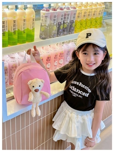Close-up of pink canvas toddler backpack with a 3D plush bear charm on cute little girl