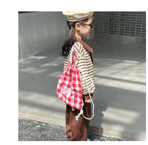 Detail of red and white checkered canvas drawstring backpack worn by a child child model