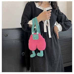 Detail showing the intricate crochet texture of a pink overall-shaped mini crossbody bag
