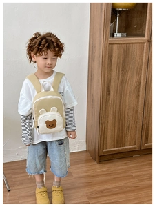 Vue détaillée d'un sac à dos enfant motif ours beige porté par un petit modèle