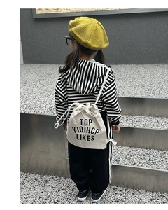 Detailed back view of a minimalist canvas drawstring backpack on a child in trendy outfit