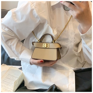 Dettaglio della mini borsa trapezoidale beige con chiusura a scatto e catena dorata