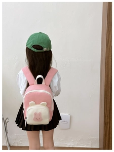 Sac à dos lapin rose et beige porté par un enfant dans une pièce au style minimaliste