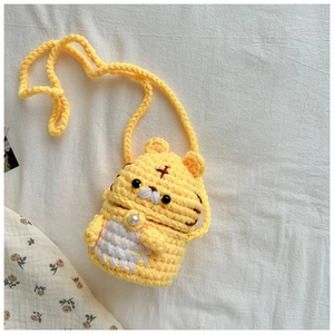 Détail du sac tigre en tricot fait main avec fermoir perle sur tissu blanc