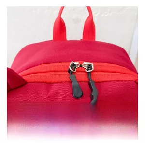 Close-up of red canvas backpack featuring smooth dual zippers and durable carry handle