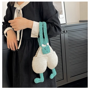 Detailed macro of handmade crochet overall trousers bag with green straps and cute legs