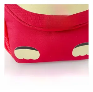 Detail of red canvas backpack featuring yellow paw prints and lucky red ribbon tag