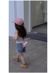 Mini sac bandoulière rose avec nœud et chaîne dorée porté par un enfant en extérieur
