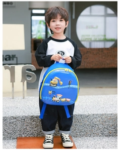 Kleiner Junge hält einen blauen Cartoon-Rucksack mit Bagger- und Zugmotiven