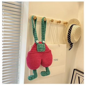 Detail of handmade crochet crossbody bag featuring cartoon overalls design and vibrant colors
