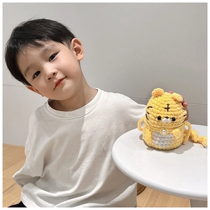 Sac tigre mignon fait main au crochet montré avec un enfant assis à table à la maison