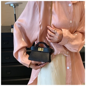 Dettaglio ravvicinato di una mini borsa in pelle nera con chiusura a scatto in metallo dorato