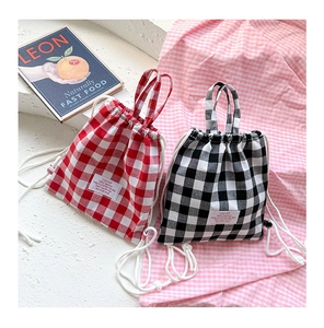 Detail of red and black checkered canvas mini backpacks with drawstrings and cloth labels