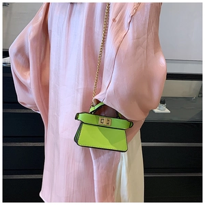 Dettaglio della mini borsa a tracolla verde neon con catena dorata e chiusura girevole