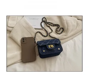 Dettaglio mini borsa a tracolla in denim trapuntato con catena oro e smartphone