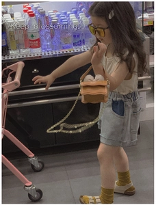Détail du mini sac bandoulière enfant orange caramel avec bord festonné et chaîne dorée