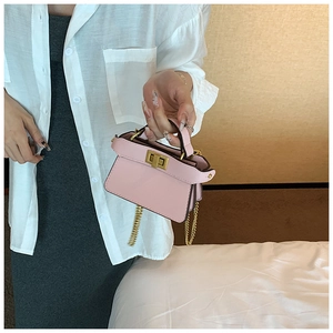 Dettaglio di una mini borsa in pelle rosa con chiusura a scatto dorata e catenella