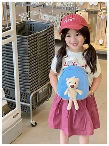 Blue canvas mini backpack for kids featuring a cute plush bear doll on the front pocket