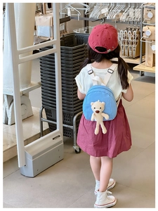 Blue mini kids canvas backpack with cute plush bear toy shown on child model