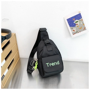 Detail of black nylon chest bag with green Trend text and adjustable shoulder strap