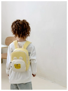 Détail du sac à dos enfant jaune et beige avec un joli écusson d'ours en peluche