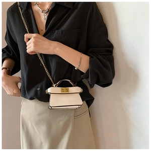 Dettaglio mini borsa a tracolla panna con catena dorata e chiusura a girello in metallo