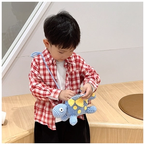 Detail of handmade knit dinosaur crossbody bag for kids with yellow scales and thin strap