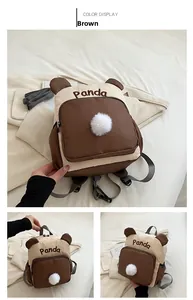 Detail des Panda-Rucksacks mit braunen Kontrastfarben, Pompons und Panda-Stickerei