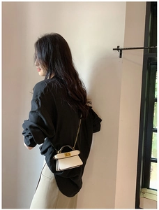 Dettaglio di una mini borsa beige a tracolla con catena dorata e chiusura a girello