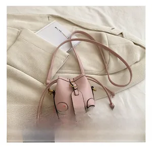 Detailed shot of pink pebble leather bucket bag featuring drawstring and metal buckle closure