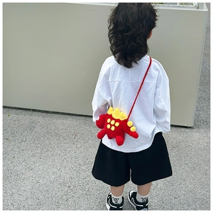 Rear view of a child wearing a handmade red crochet dinosaur bag with yellow fins