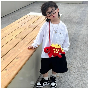 Toddler wearing a red handmade knitted dinosaur crossbody bag on a casual white t-shirt