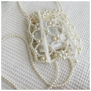 Détail d'un sac à perles fait main avec doublure en satin blanc et bandoulière longue