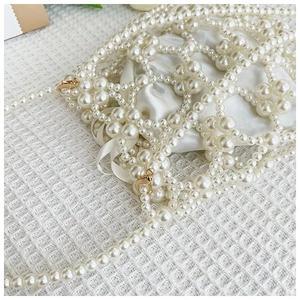 Détail d'un sac en perles blanches fait main avec doublure en satin et chaîne dorée