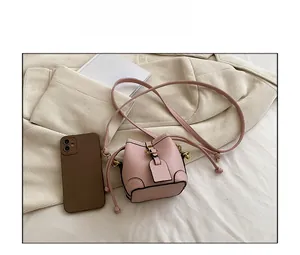 Pink mini bucket bag shown next to a smartphone to demonstrate compact portable size