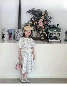 Detail of floral baby girl dress featuring puff sleeves and lace waist ruffles