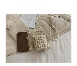 Close-up of handmade white pearl bucket bag with gold accents and drawstring closure