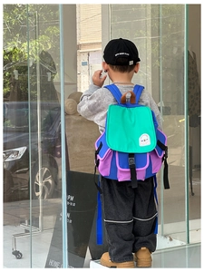 Rear view of a child wearing a colorful canvas backpack with bright blue straps
