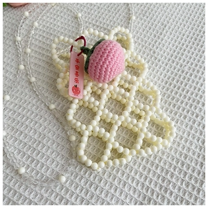 Detail of handmade beaded girl's crossbody bag with crochet peach and blessing tag