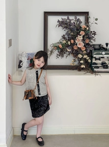 Detailed close-up of girls tweed vest and black sequin skirt outfit in a lifestyle setting