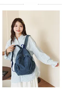 Lifestyle view of a vintage denim backpack with multiple compartments worn by a student