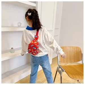 Kids red chest bag with cartoon dinosaurs shown on child back for size reference