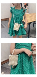 Detail of handmade white pearl woven mini bucket bag for girls with golden accents
