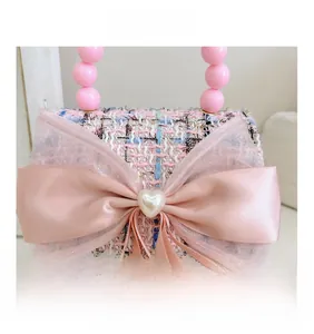 Détail du mini sac fille en tweed rose avec nœud satiné et bouton perle cœur