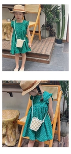 Detail of girl's woven pearl bucket bag and straw hat with forest green polka dot dress