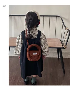 Detail of child wearing caramel crochet mini bag with round handle and shoulder strap