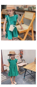 Close-up of vibrant green polka dot girls' dress with ruffle sleeves and pleated detail